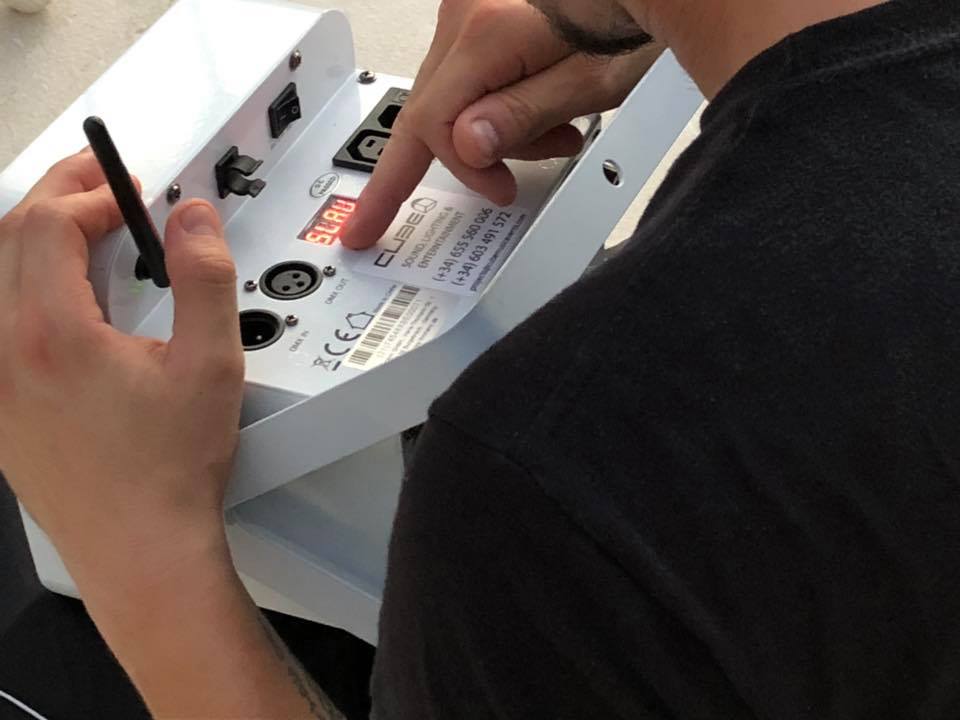 Person setting up a device with digital display and various ports.